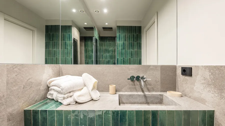 Bagno Santopaolo 5 con lavabo in pietra, ceramica verde smeraldo e specchio a tutta parete